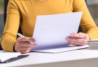 Close-up of a woman signing papers for birth certificate attestation – NRIWAY company services.