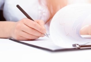 A person reviewing and signing official documents on a clipboard, symbolizing certificate verification.