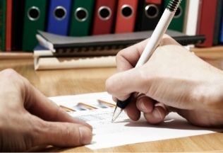 Student writing a syllabus with folders in the background