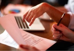 Professionals reviewing documents with a laptop, representing NRIWAY company’s document attestation and consultation services.